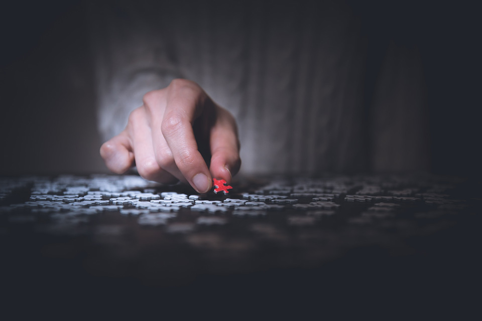Man working on puzzle, one red piece